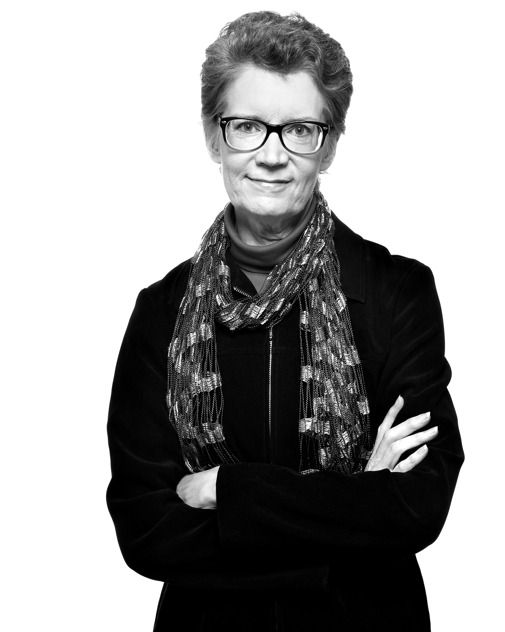 A black and white image of Christine Peterson smiling confidently while folding her arms.